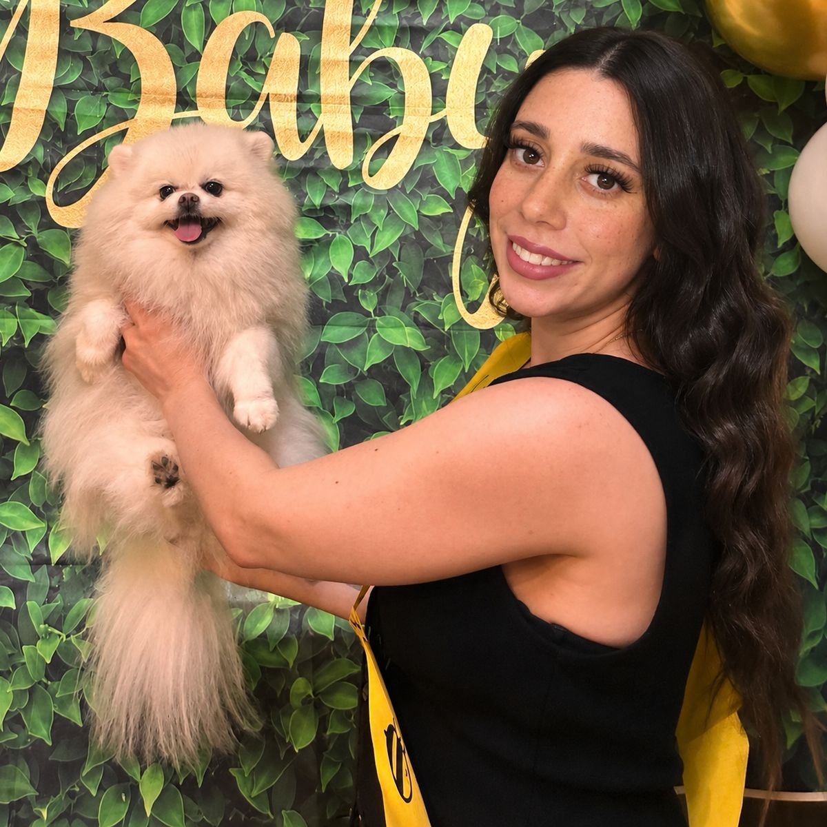 Pamela, the owner of Petite Paws, smiling and holding a cream Pomeranian
